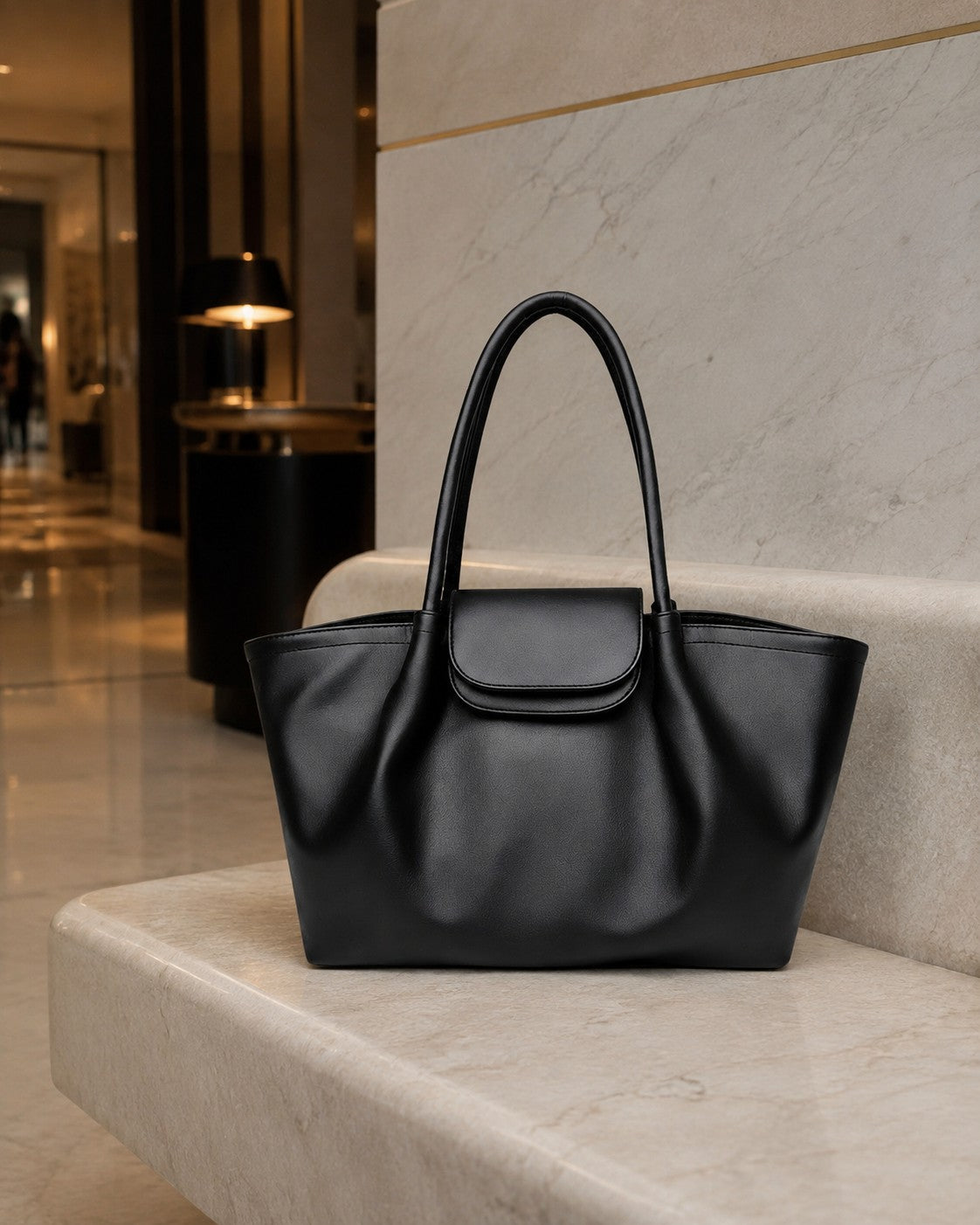 VALENORA Amara black vegan leather tote bag with a structured silhouette, dual shoulder straps, and buckle flap.