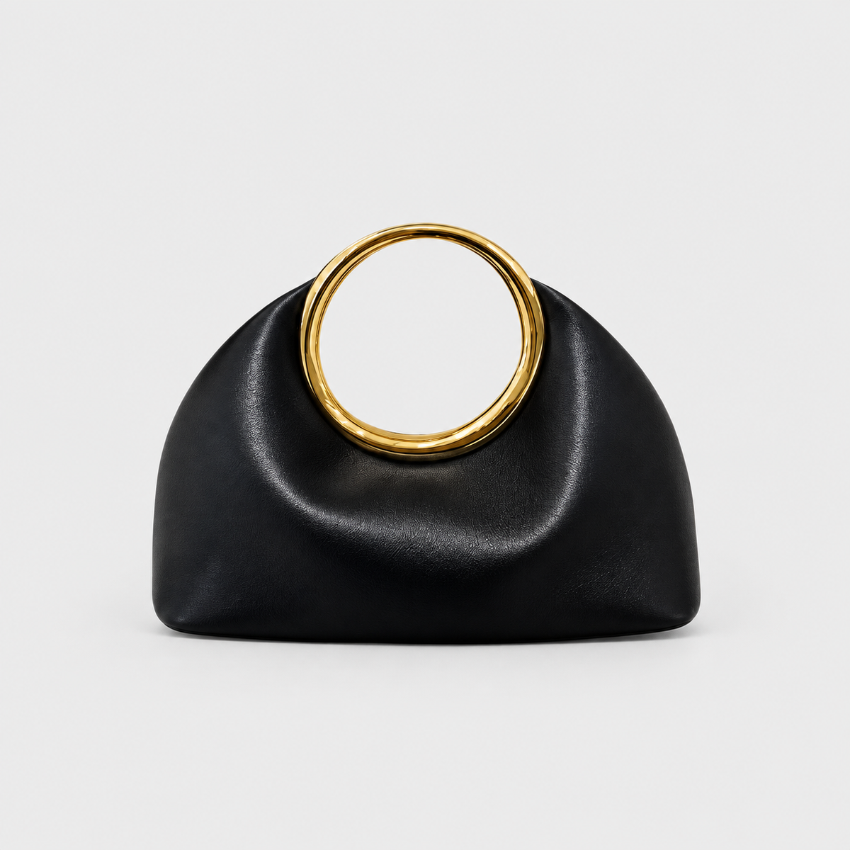 VALENORA Aurea small black vegan leather handbag with a polished gold circular metal handle on a white background.