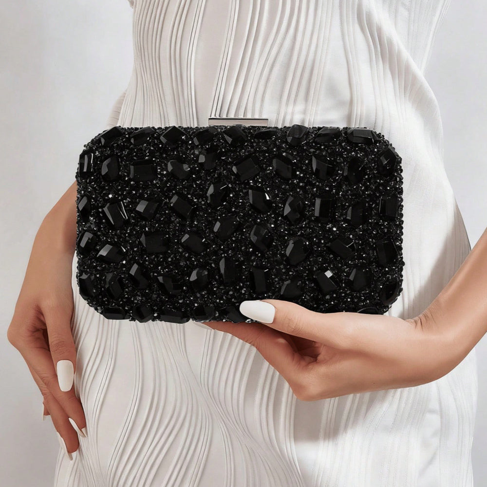 VALENORA Aurelina black rhinestone clutch bag with a buckle closure held by a woman in a white dress