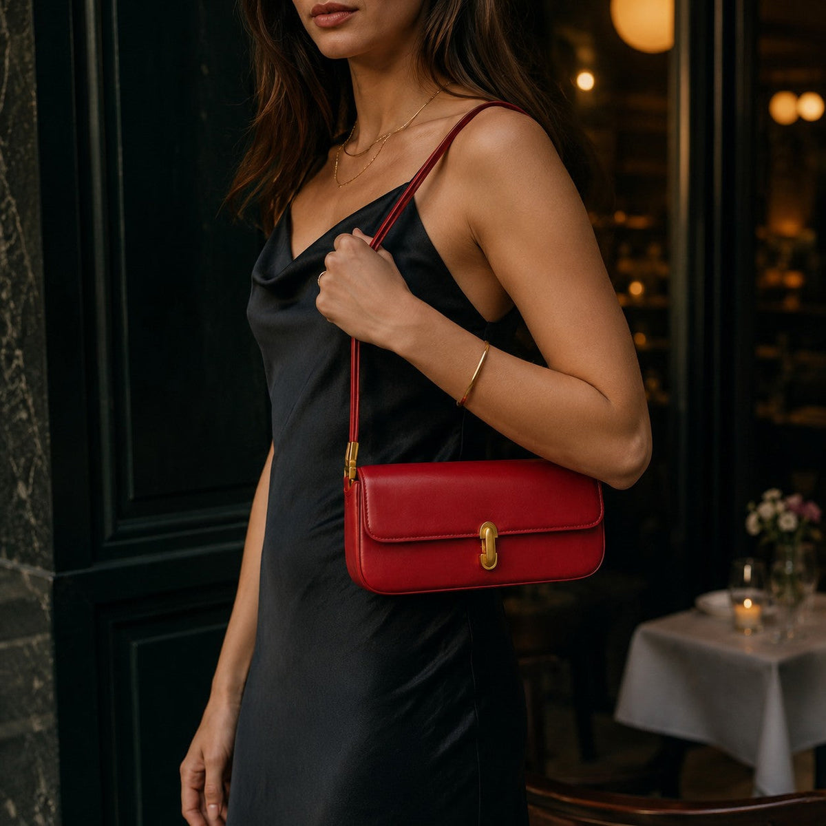 VALENORA Bianca shoulder bag in red microfiber leather with a gold link clasp, worn by a woman in a black dress.