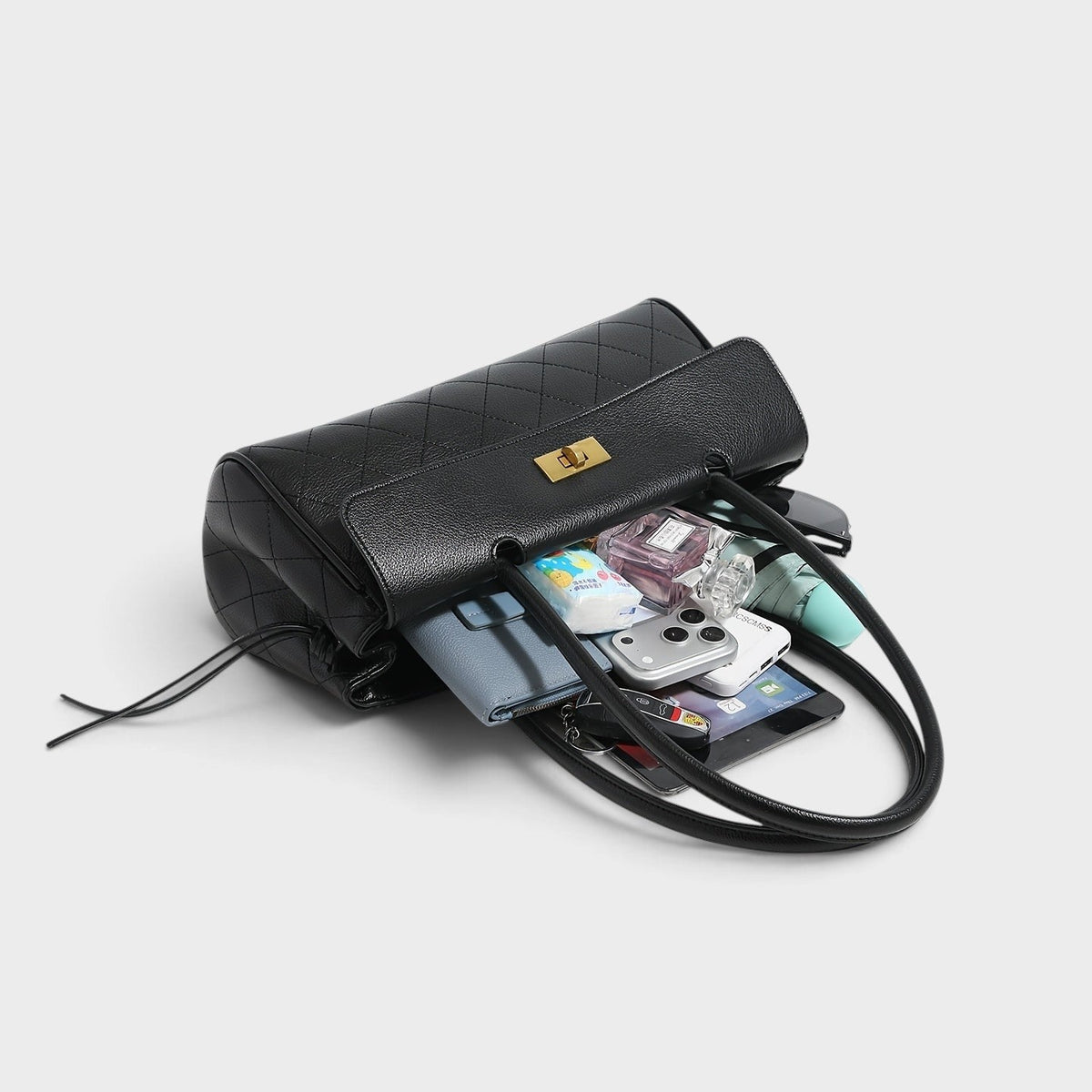 VALENORA black quilted shoulder bag with gold turn-lock closure and side-tie detail, shown open with daily essentials.
