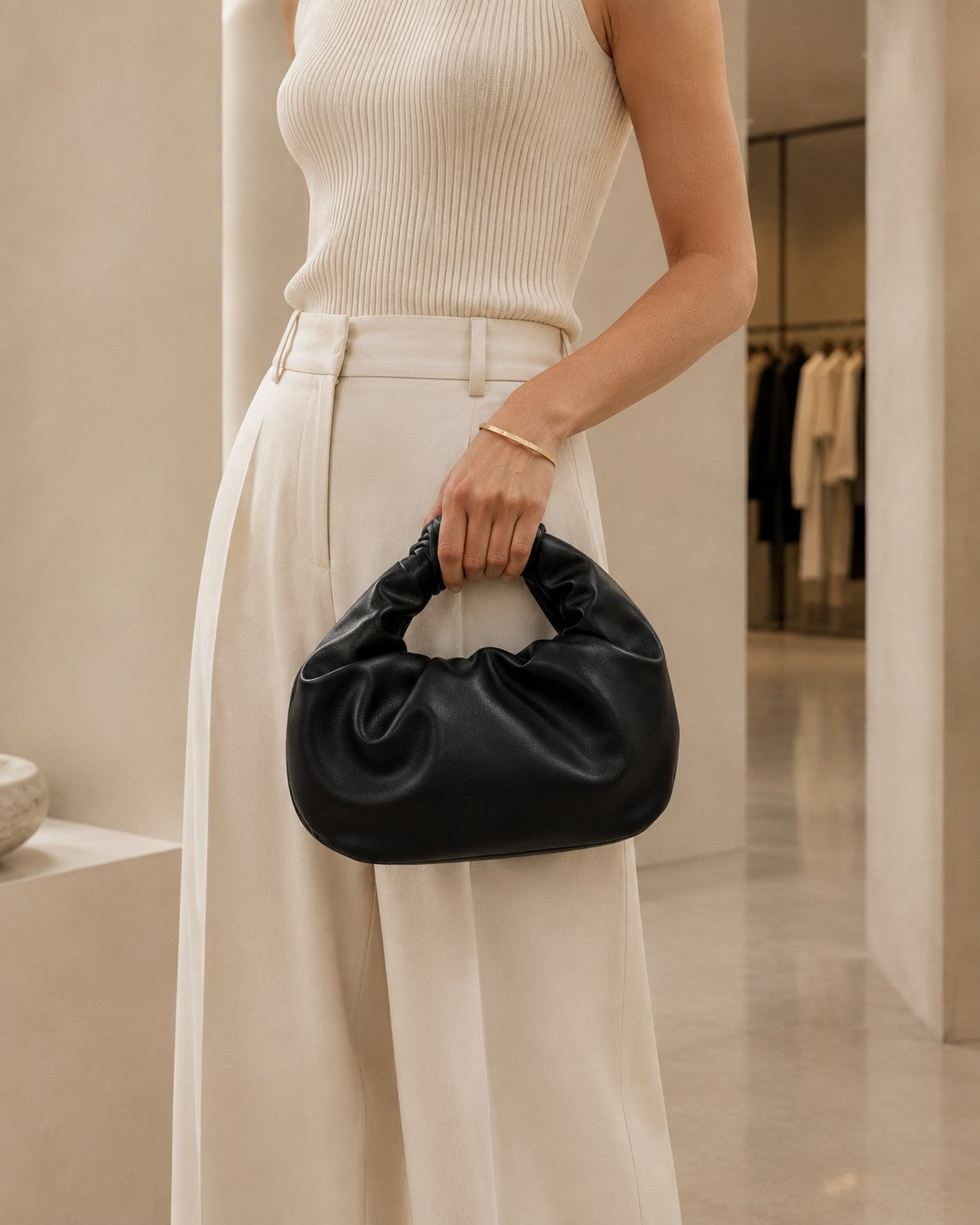 VALENORA black matte vegan leather handbag with a gathered handle held by a woman in a neutral outfit