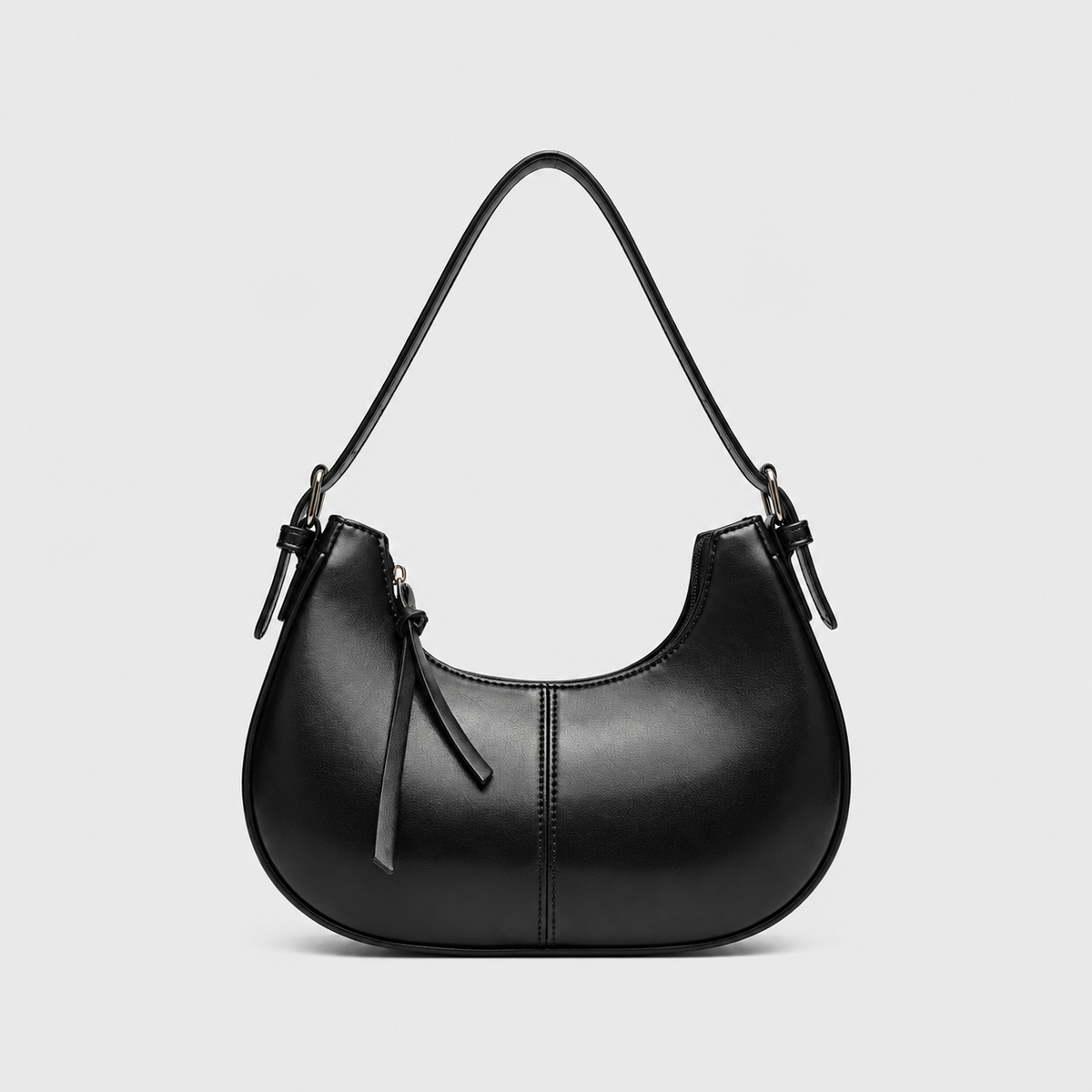 VALENORA black vegan leather shoulder bag with a rounded silhouette, zip closure, and decorative fringe pull.