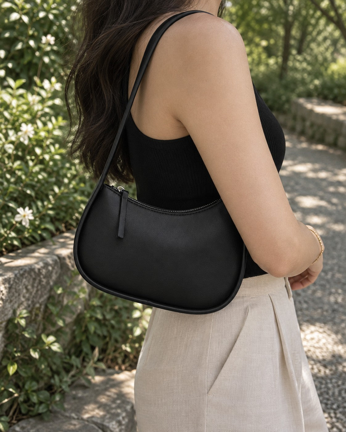 VALENORA Brooklyn shoulder bag in black genuine leather with a crescent shape and gold-tone zipper, worn on shoulder.