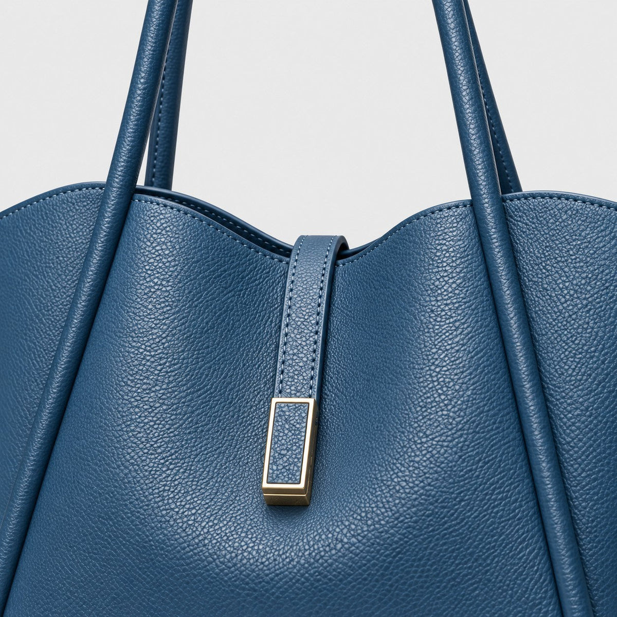 VALENORA Charlotte tote bag in blue litchi-grain vegan leather with a curved top and gold hardware tab detail