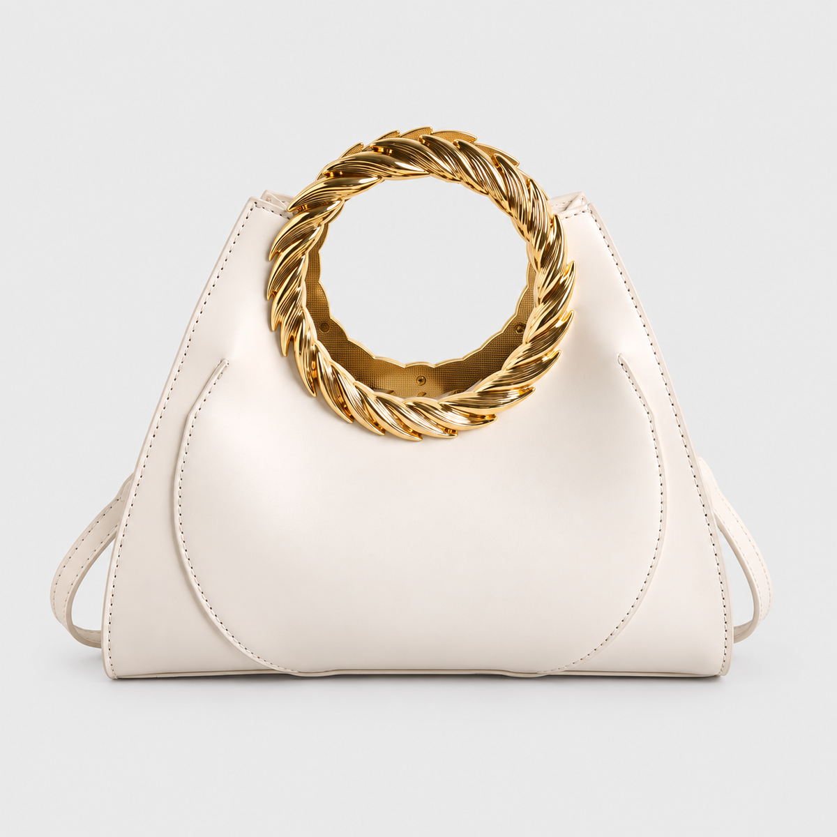 VALENORA Cleo handbag in off-white vegan leather with a bold, twisted gold ring handle and minimalist design.