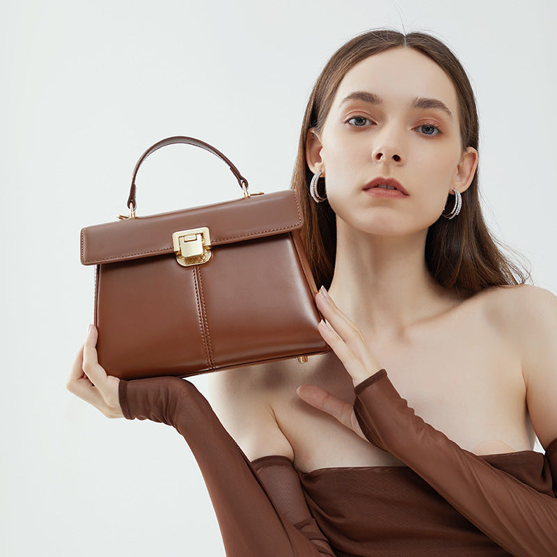 VALENORA Henna dark brown genuine leather structured crossbody handbag with gold clasp held by a model