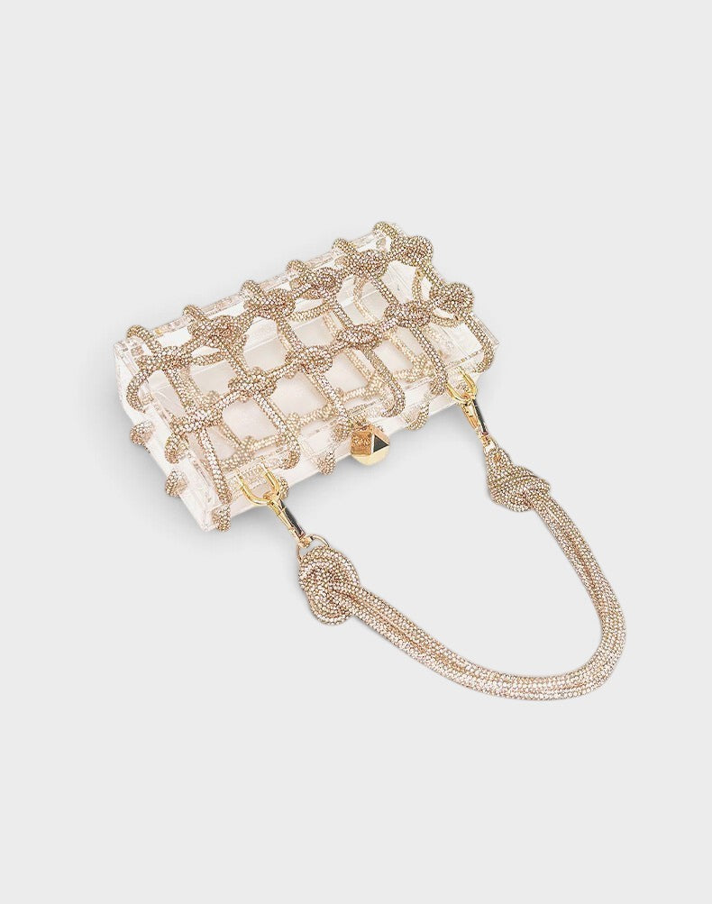 VALENORA Isabelle clear acrylic clutch bag with gold crystal-embellished grid overlay and matching crystal handle.