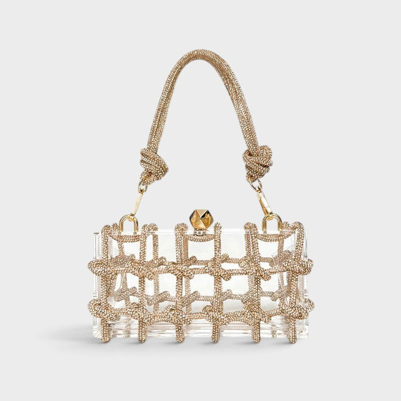 VALENORA Isabelle clear acrylic clutch bag with gold crystal-embellished grid overlay and matching top handle