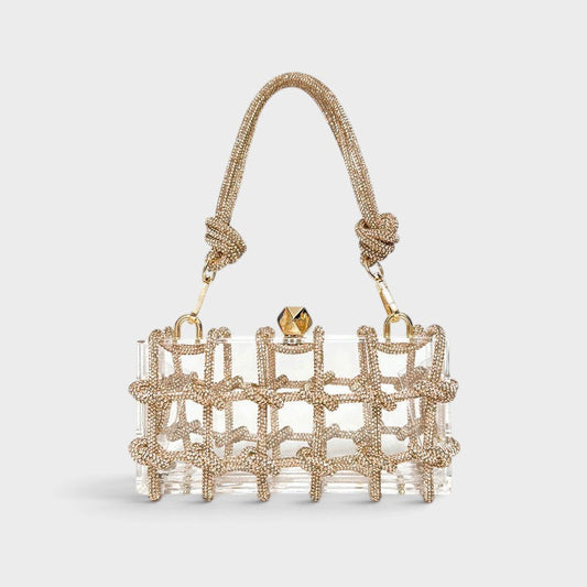 VALENORA Isabelle clear acrylic clutch bag with gold crystal-embellished grid overlay and matching top handle