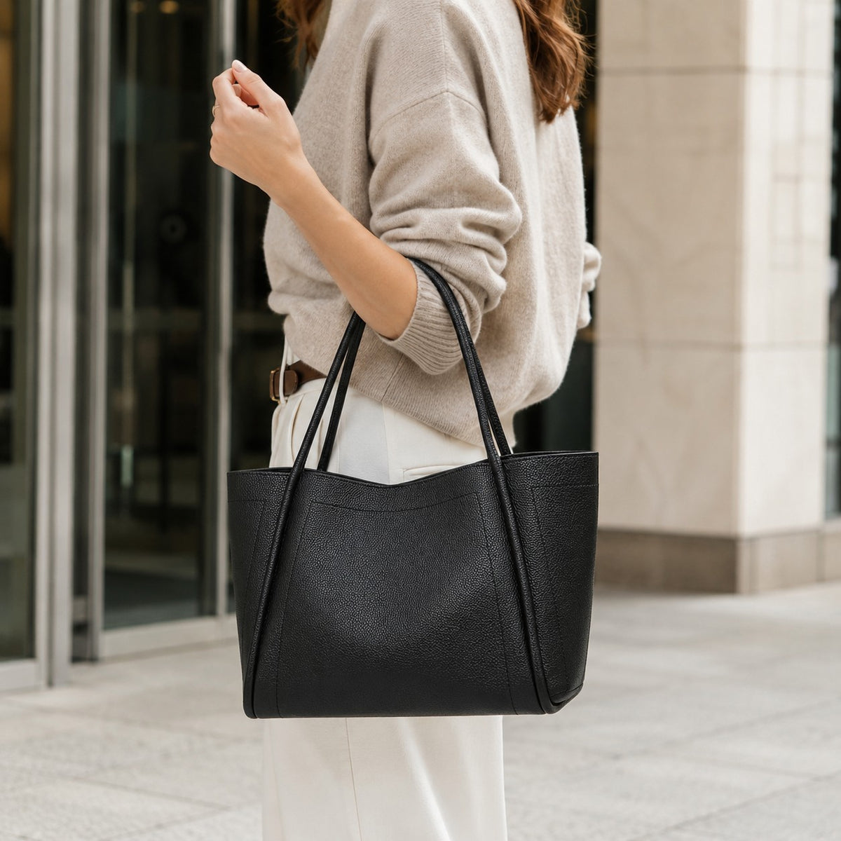 VALENORA Kate black vegan leather tote bag with dual top handles carried by a woman in a neutral outfit