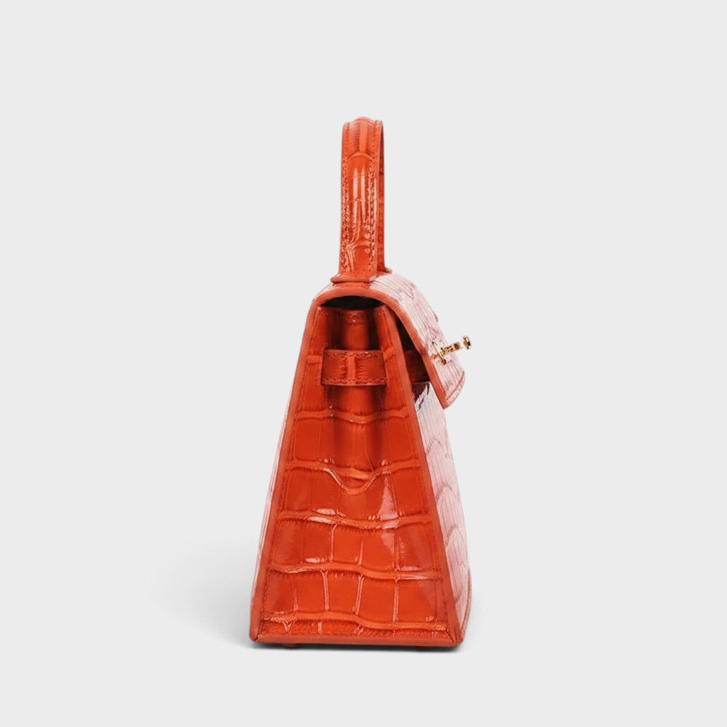 VALENORA Kelly orange genuine leather crossbody handbag with a textured crocodile-embossed finish, side view.