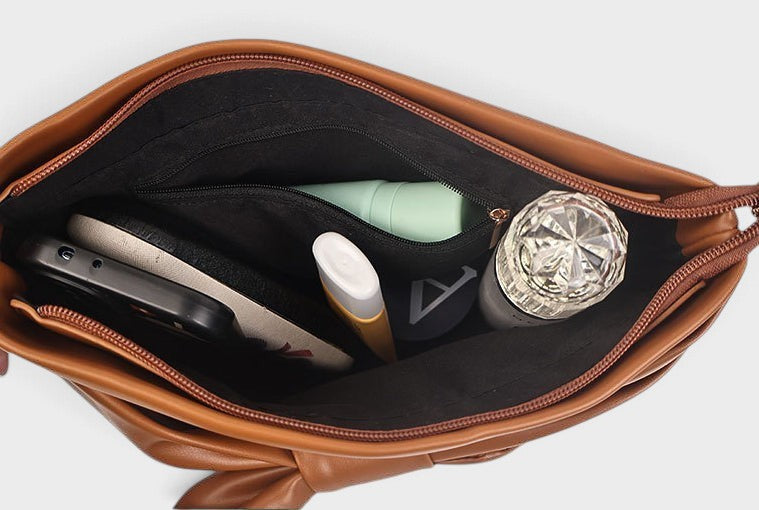VALENORA leather handbag interior view showing black fabric lining with zippered pocket and organized daily items