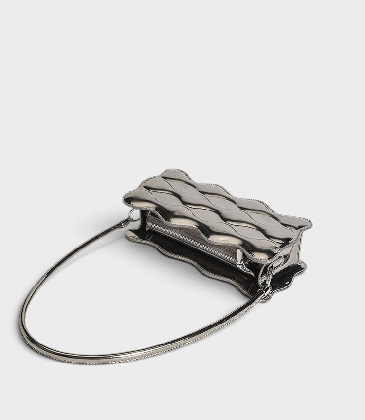 VALENORA Luna Wave shoulder bag in metallic silver vegan leather with a unique sculptural curved silhouette.