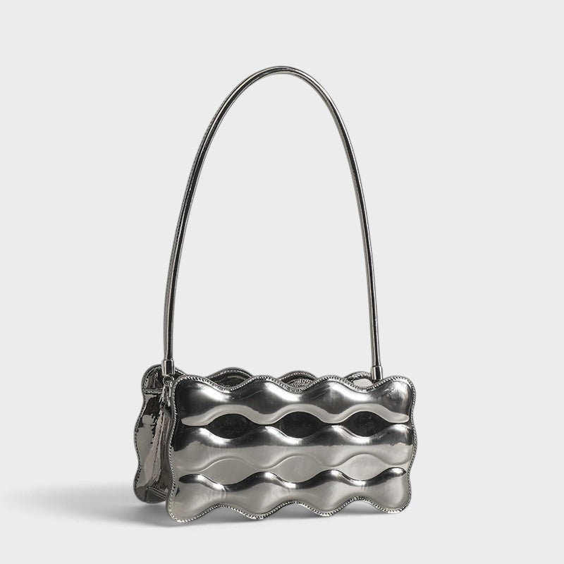 VALENORA Luna Wave shoulder bag in metallic silver vegan leather with a unique sculptural curved silhouette.