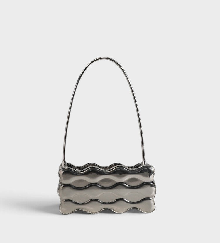 VALENORA Luna Wave shoulder bag in metallic silver vegan leather with a sculptural curved silhouette.