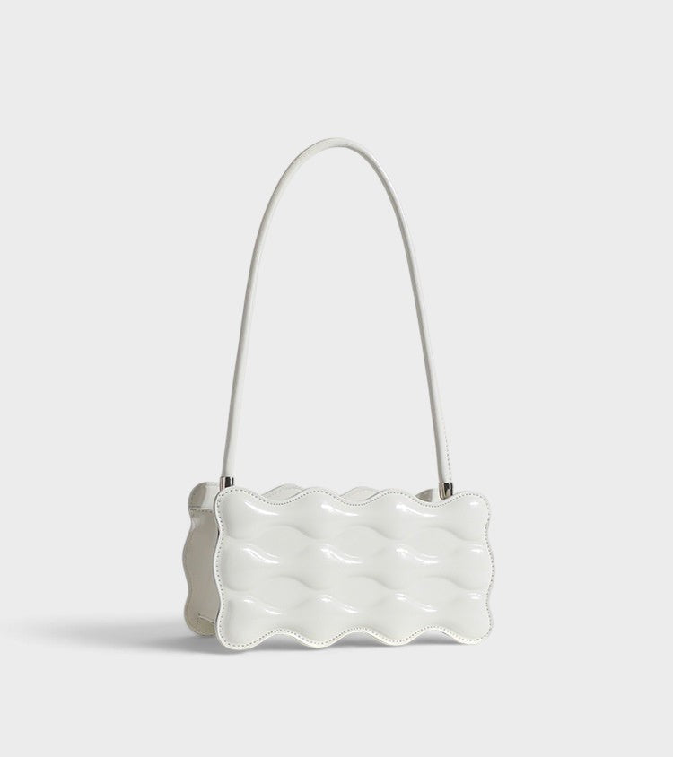 VALENORA Luna Wave shoulder bag in glossy white vegan leather with a unique sculptural curved silhouette.