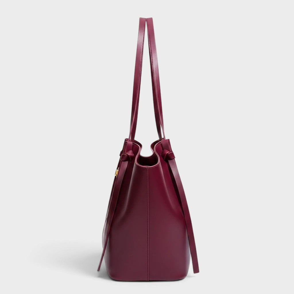 VALENORA Madison burgundy leather tote bag with a sculptural knotted top handle, side view.