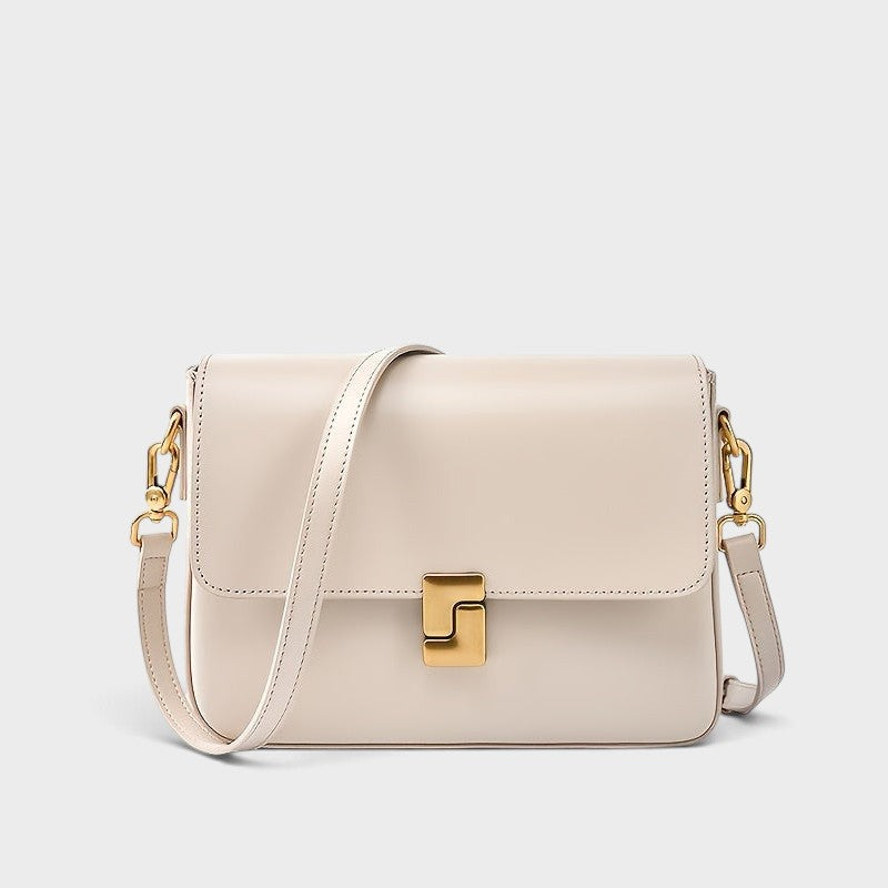 VALENORA Marisa shoulder bag in beige cowhide leather with a sculptural gold-tone buckle and adjustable strap.
