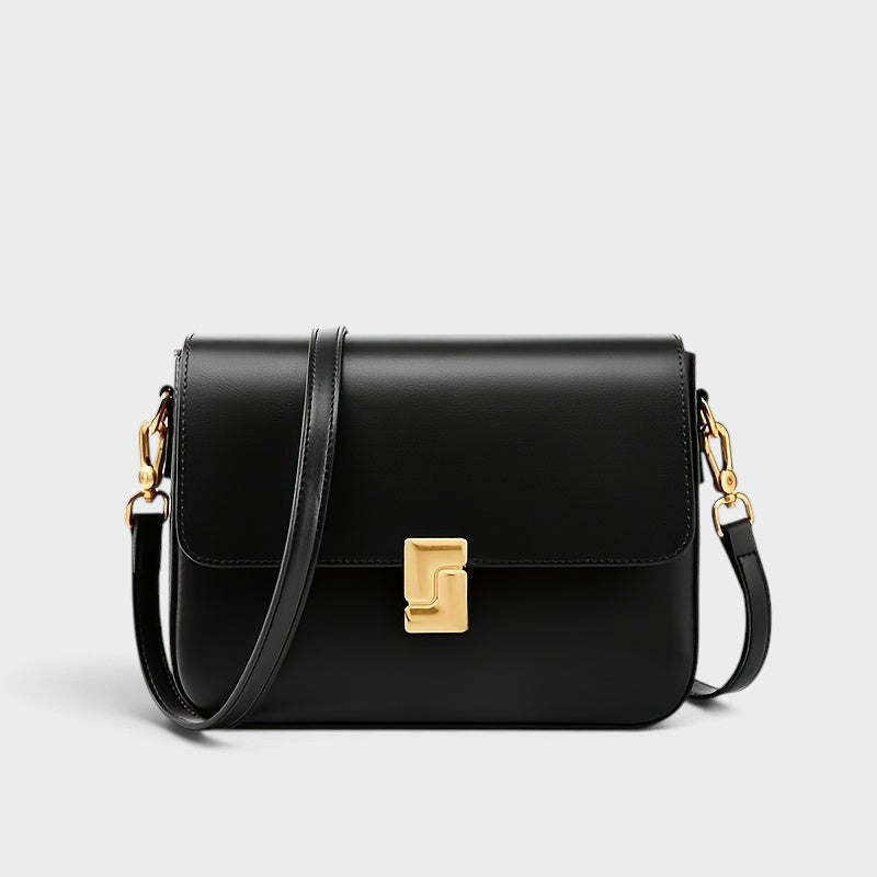 VALENORA Marisa black genuine cowhide leather shoulder bag with a sculptural gold-tone buckle and adjustable strap.