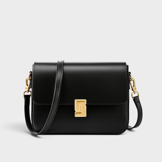 VALENORA Marisa black genuine cowhide leather shoulder bag with a sculptural gold-tone buckle and adjustable strap.