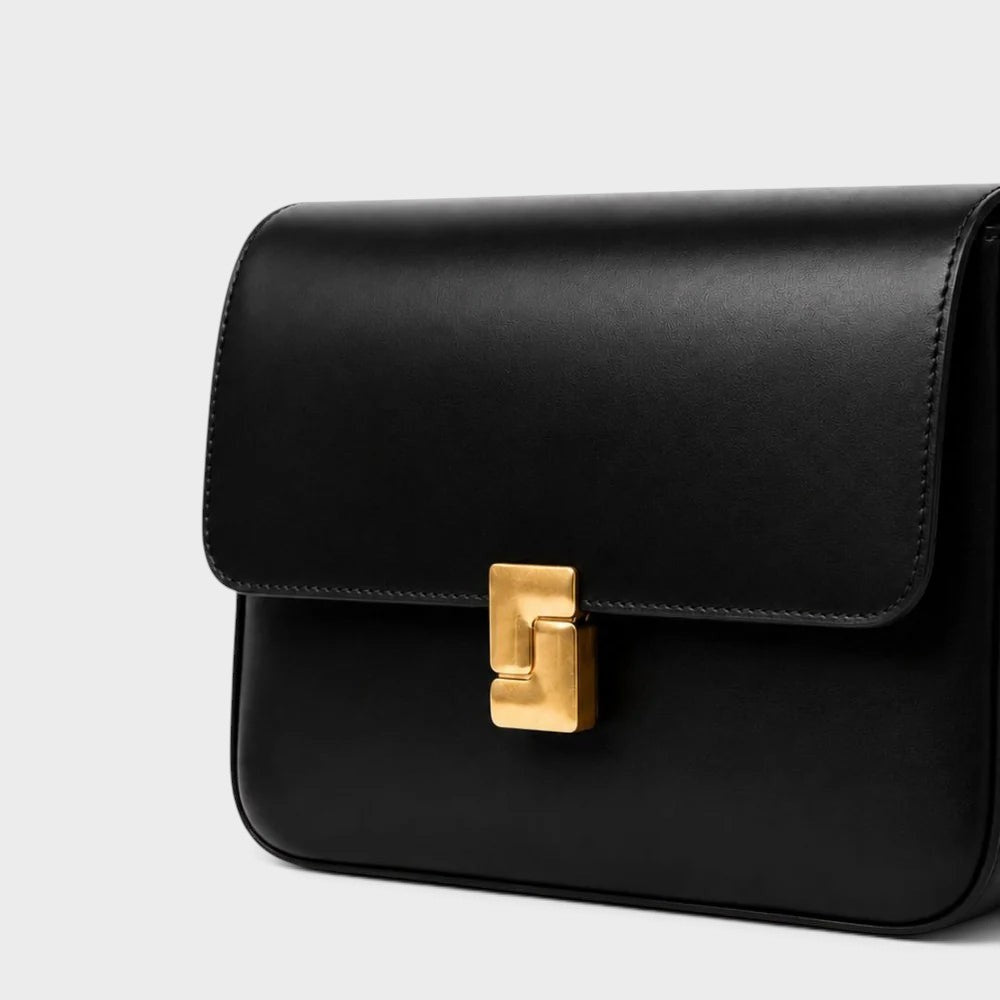 VALENORA Marisa black cowhide leather shoulder bag with a sculptural gold-tone buckle closure.