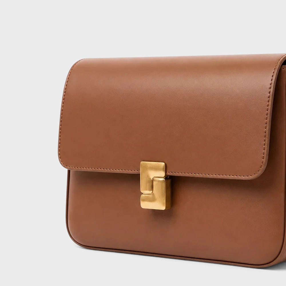 VALENORA Marisa shoulder bag in brown cowhide leather with a sculptural gold-tone buckle closure.
