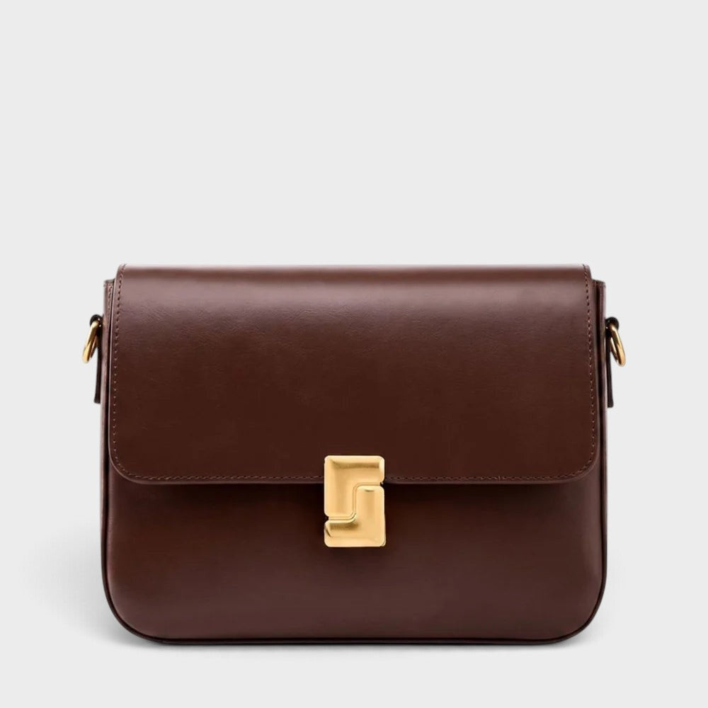 VALENORA Marisa brown cowhide leather shoulder bag with a structured flap and sculptural gold-tone buckle closure.