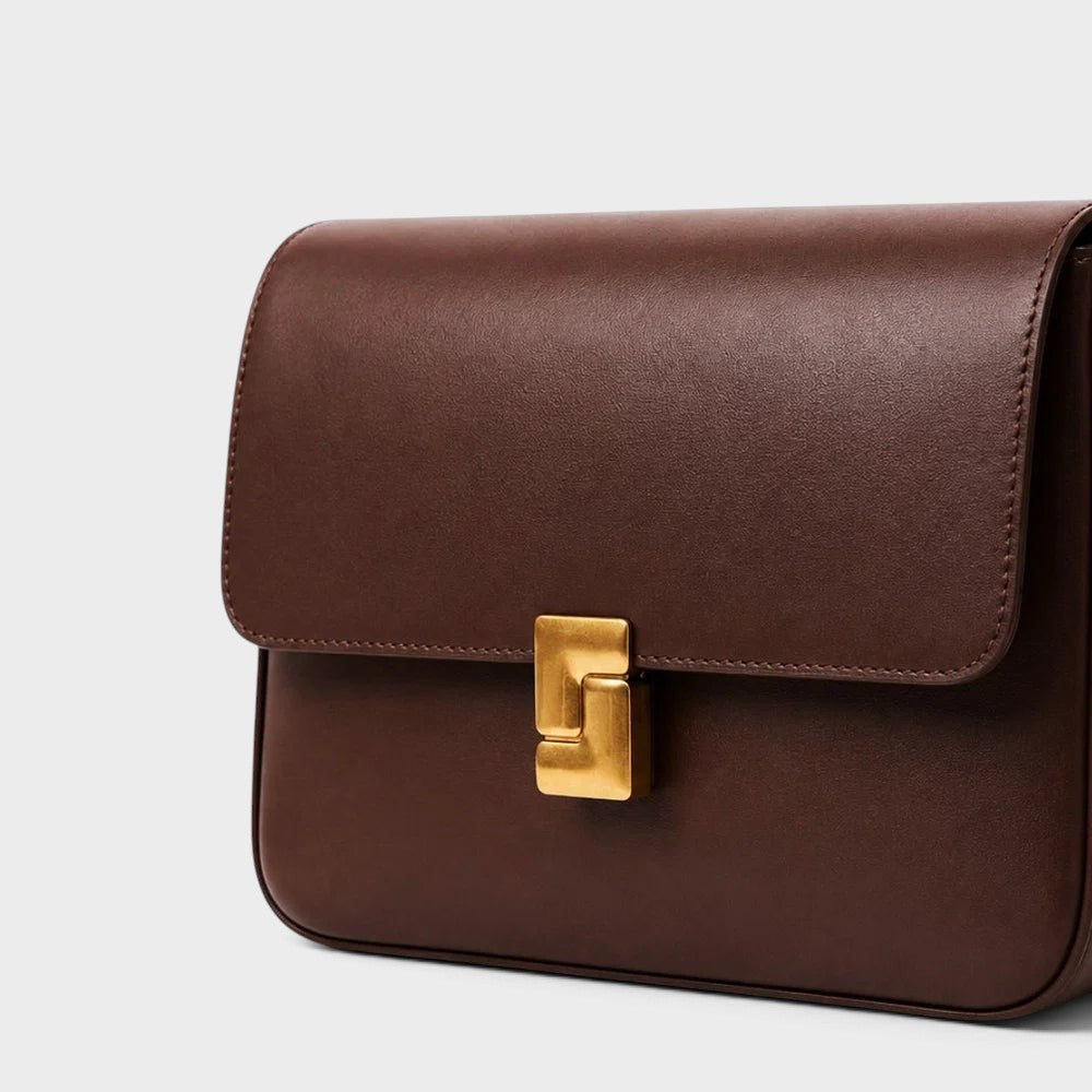 VALENORA Marisa shoulder bag in dark brown cowhide leather with a sculptural gold-tone buckle closure.