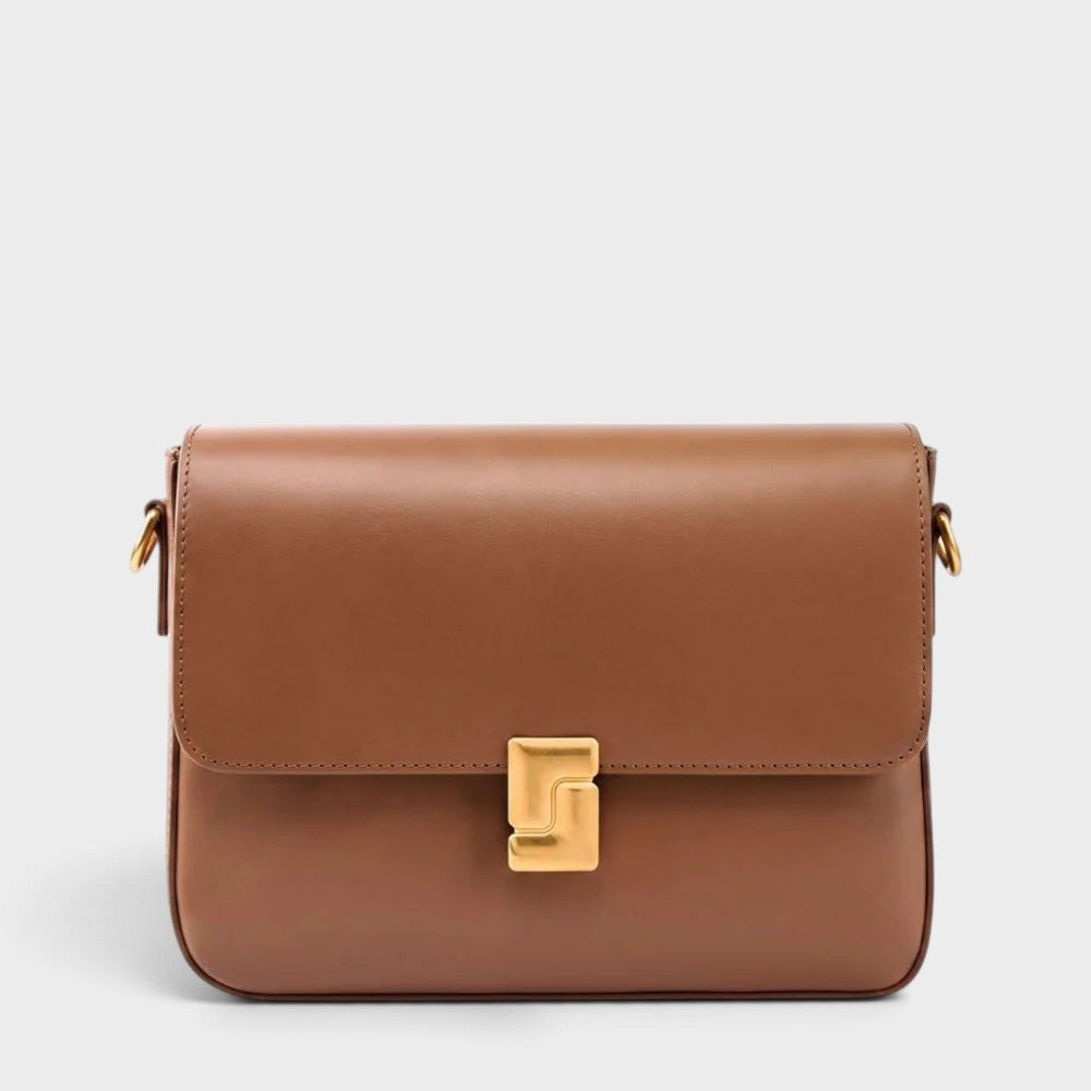 VALENORA Marisa brown cowhide leather shoulder bag with a structured flap and sculptural gold-tone buckle closure.