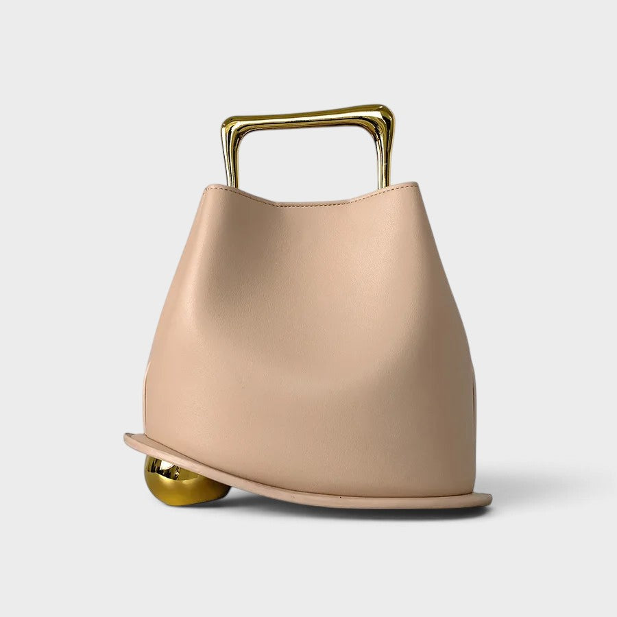 VALENORA Marisol handbag in beige with a sculptural silhouette, gold-toned metallic handle, and spherical base detail.