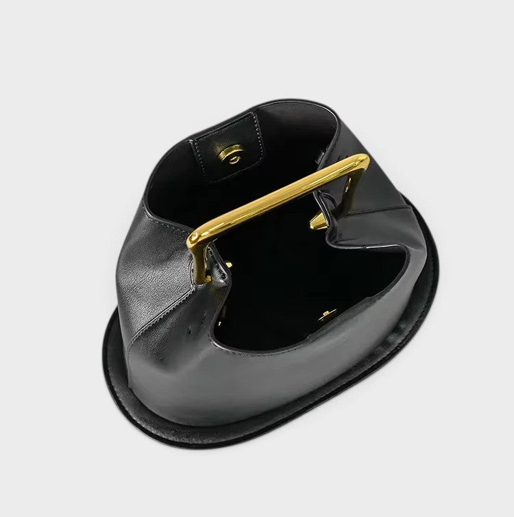 VALENORA Marisol handbag in black with a sculptural silhouette and a polished gold-tone metallic top handle.