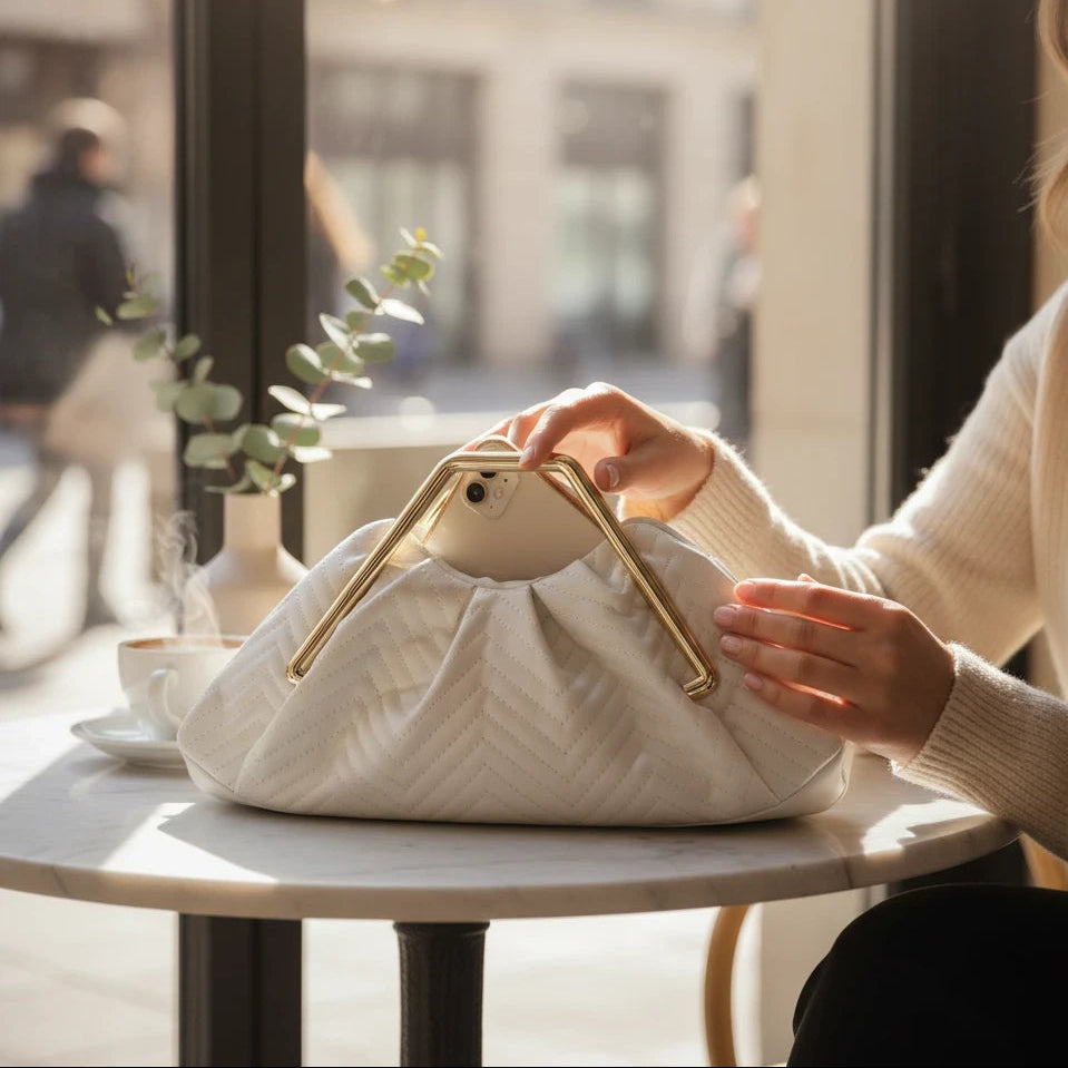VALENORA Norah white vegan leather handbag with a herringbone pattern and gold frame closure on a cafe table