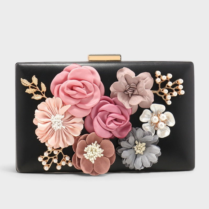 VALENORA Rosalind black hard-shell clutch with fabric flowers, pearl accents, and gold leaf details.