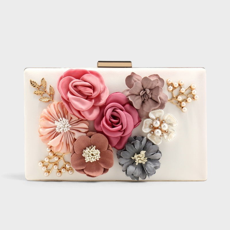 VALENORA Rosalind clutch bag in cream with fabric floral embellishments, pearl accents, and gold-tone leaf details.