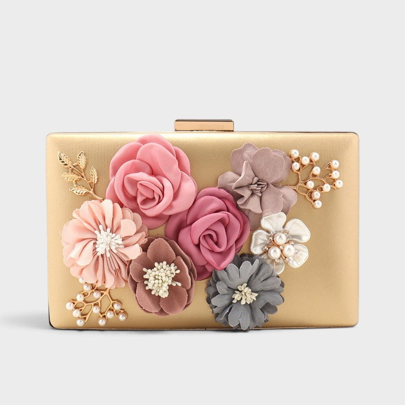 VALENORA Rosalind gold hard-shell clutch bag with fabric floral embellishments, pearl accents, and gold leaf details.