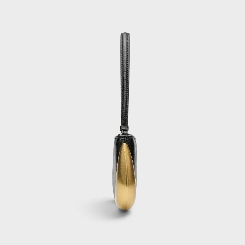 VALENORA Rosanna shoulder bag in black with a sculptural gold metallic side accent, shown from a side profile view.