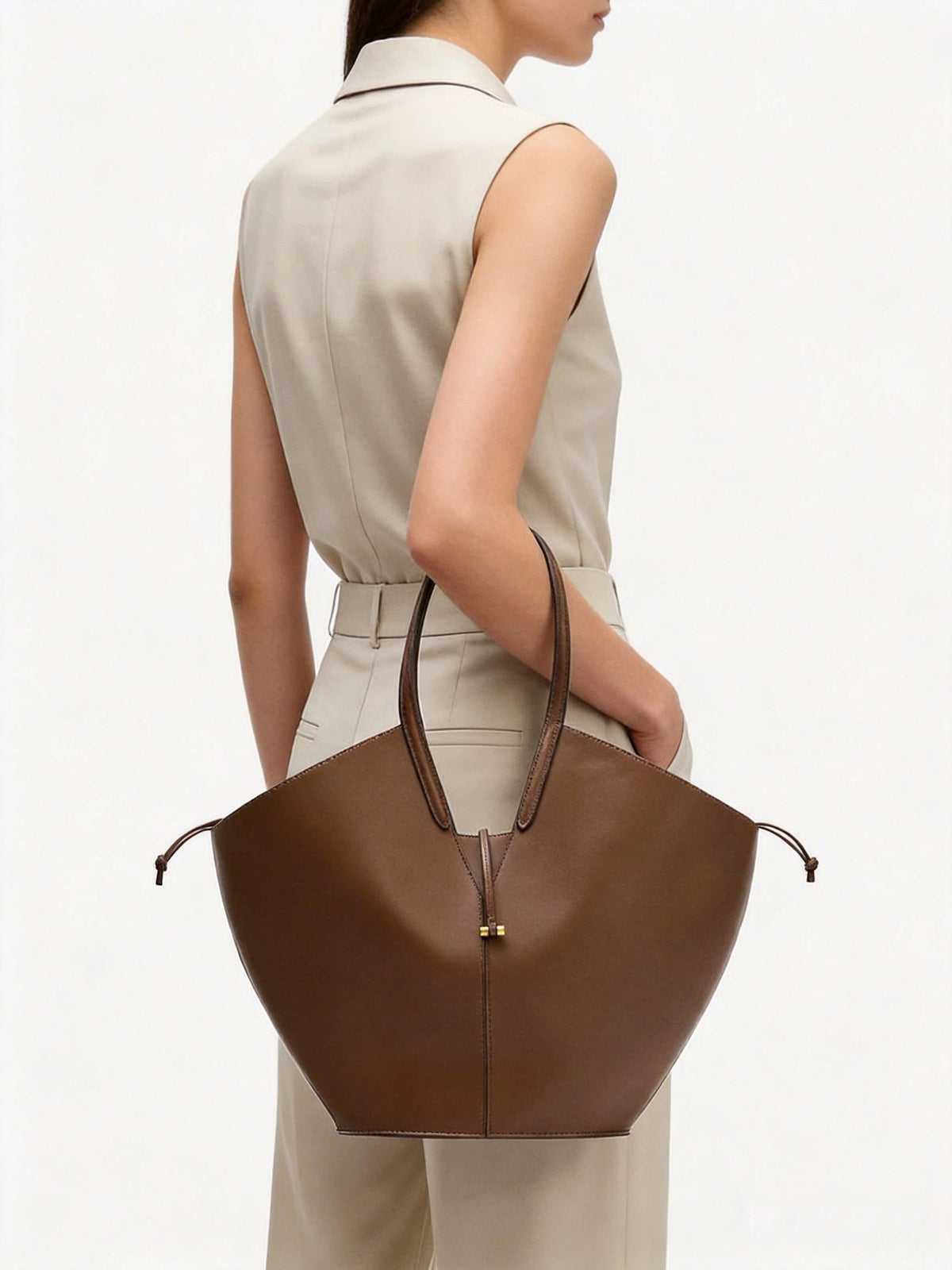 VALENORA Solene brown vegan leather tote bag with a sculptural wraparound handle and gold toggle detail.