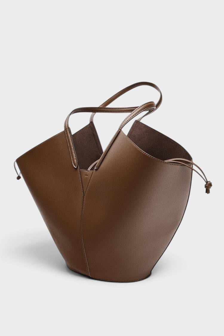 VALENORA Solene brown vegan leather tote bag with a sculptural wraparound handle and gold toggle detail.