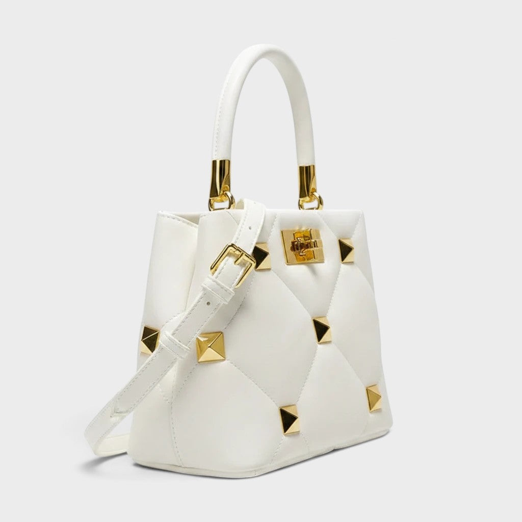 VALENORA Stella white structured leather handbag with gold pyramid studs and top handle on a plain background