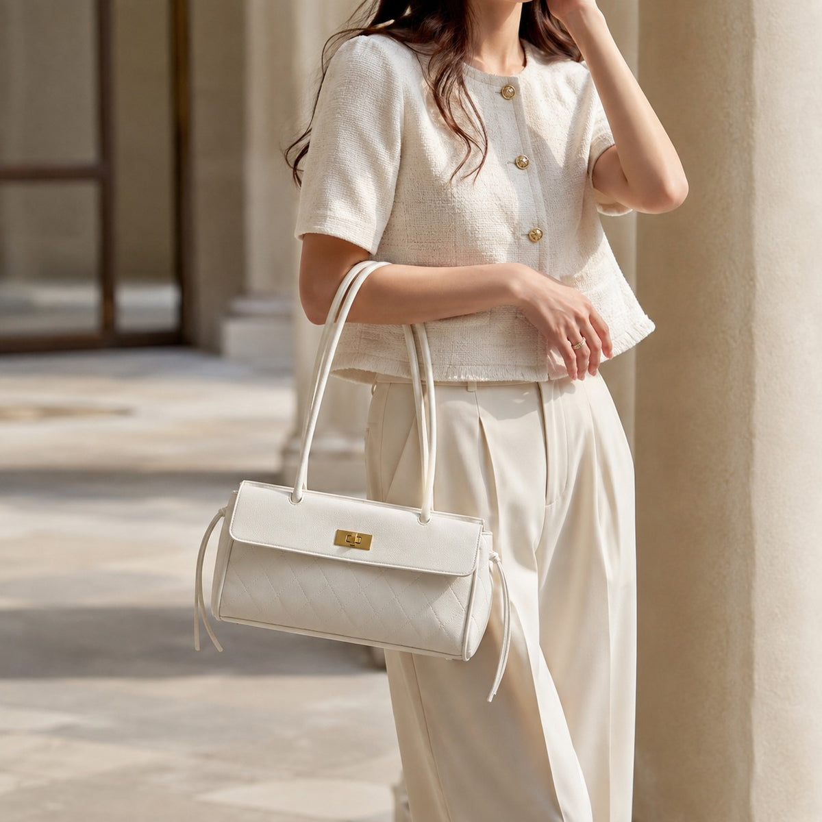 VALENORA Verancia white quilted shoulder bag with gold turn-lock closure and side-tie details worn by a woman